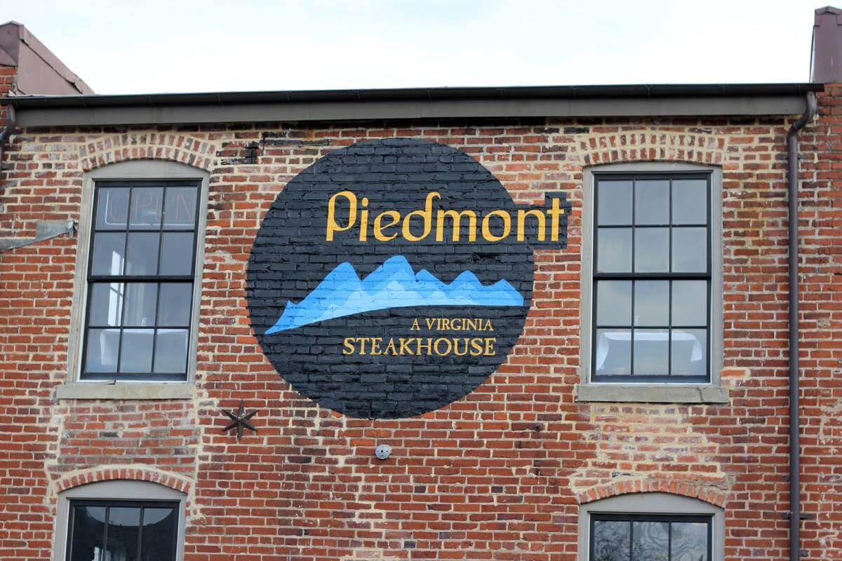 A brick building features a painted circular sign with the word 