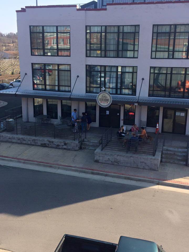 A three-story industrial building with large grid windows houses a business called 