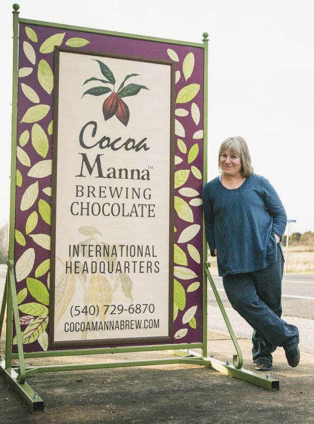 A person in a blue top and jeans is leaning against a large sign that reads 