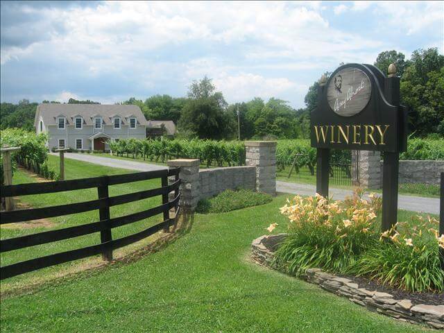 A scenic view of a winery entrance with a sign reading 