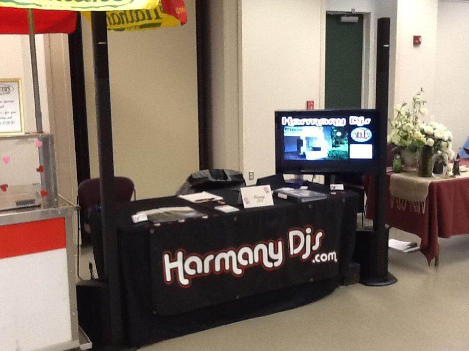 A promotional booth for Harmany DJs displays a banner with the website 