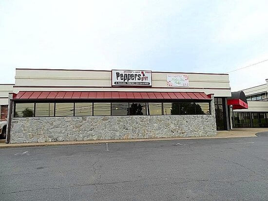 A single-story building with a stone facade and a prominent awning, under which windows stretch across its length. A sign above the awning reads 