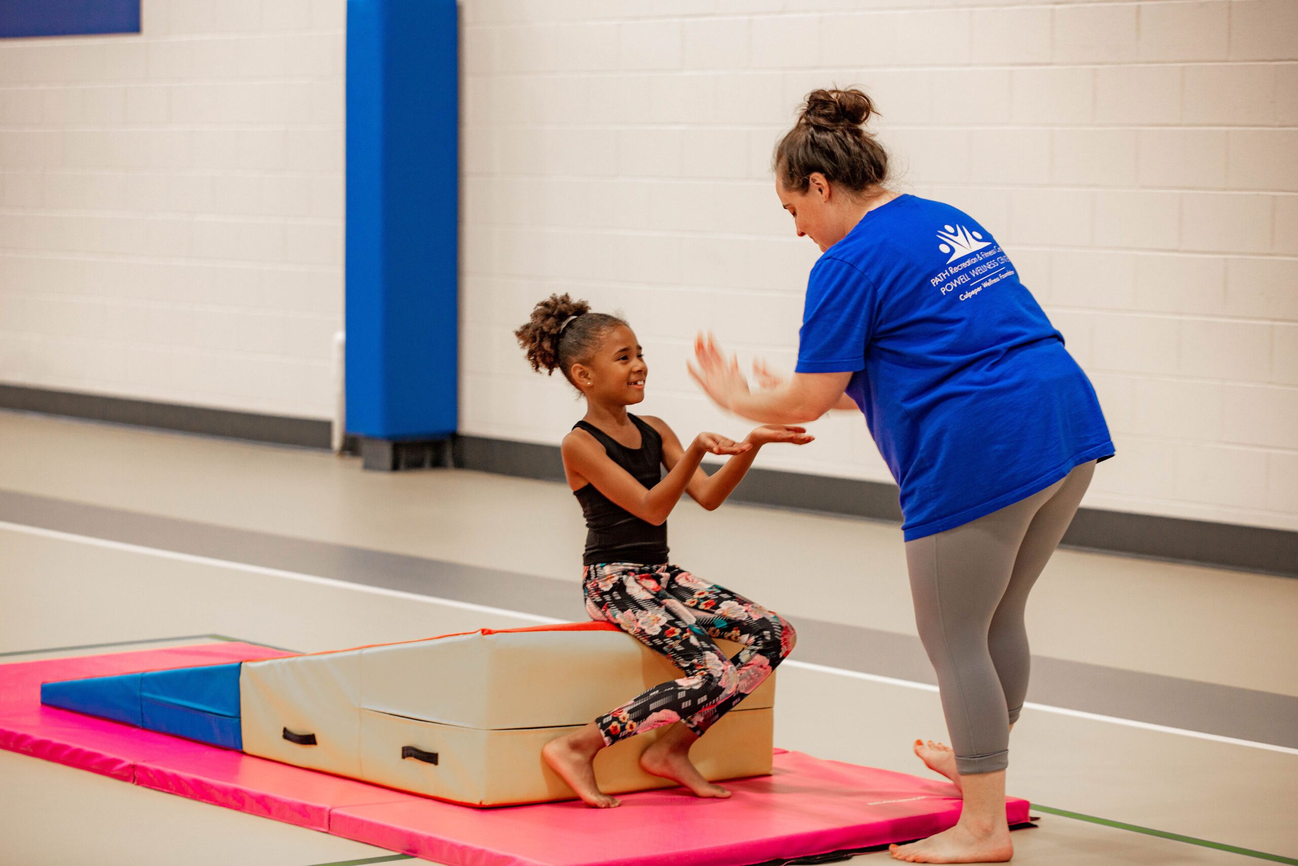 child gymnast giving instructor a high five