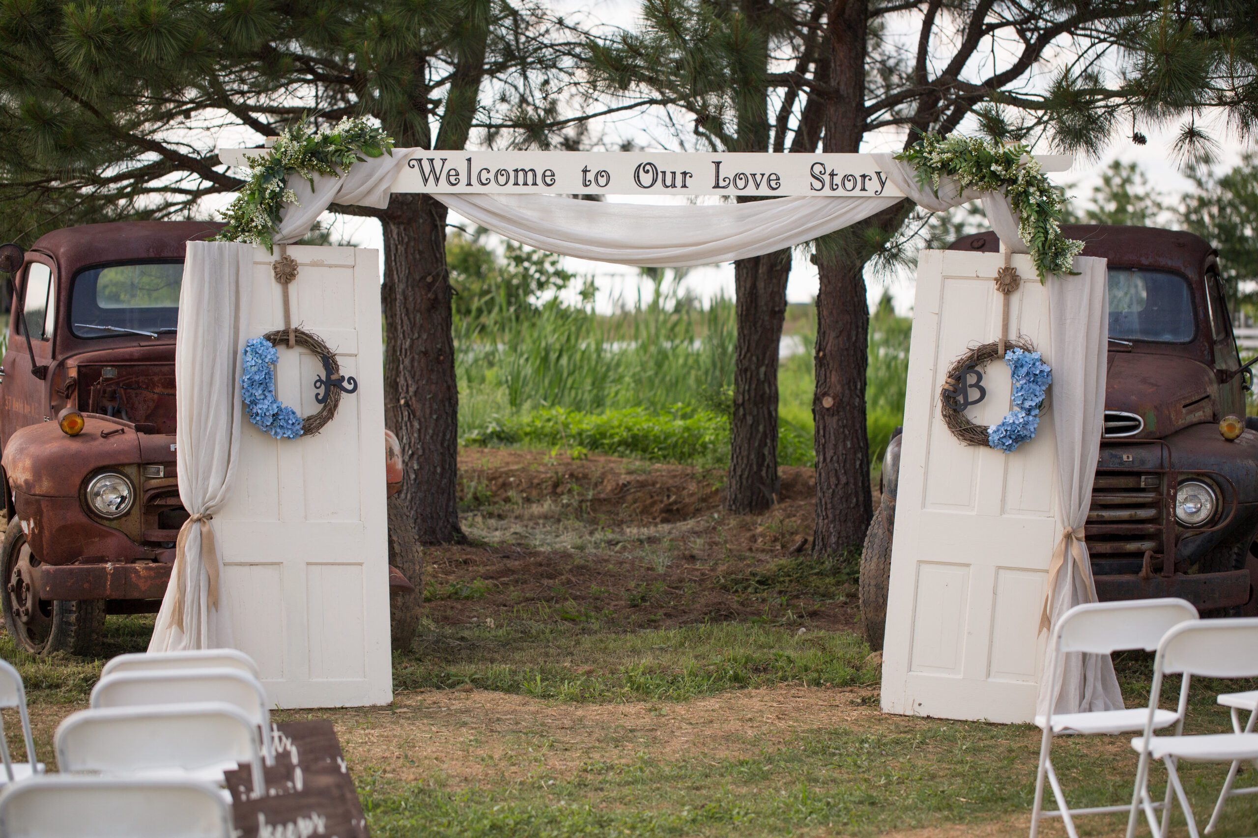 An outdoor wedding ceremony setup in one of the charming wedding venues in Virginia features two vintage doors forming an arch with a 