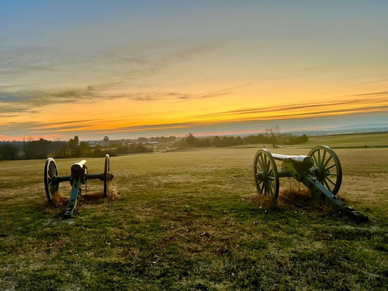 two cannons with a sunrise in the background