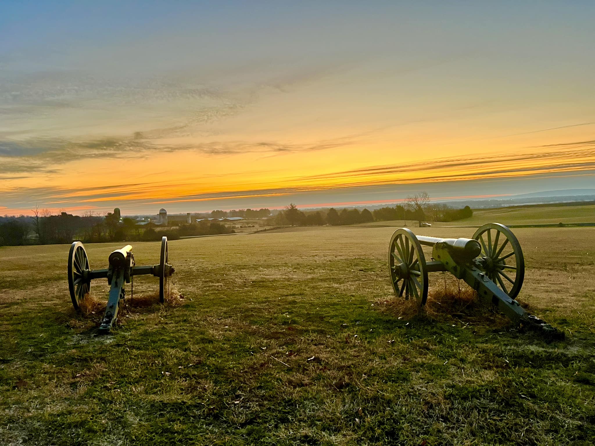 two cannons with a sunrise in the background