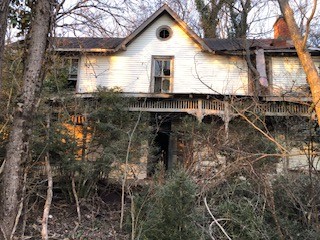 image of an old home with trees grown up around