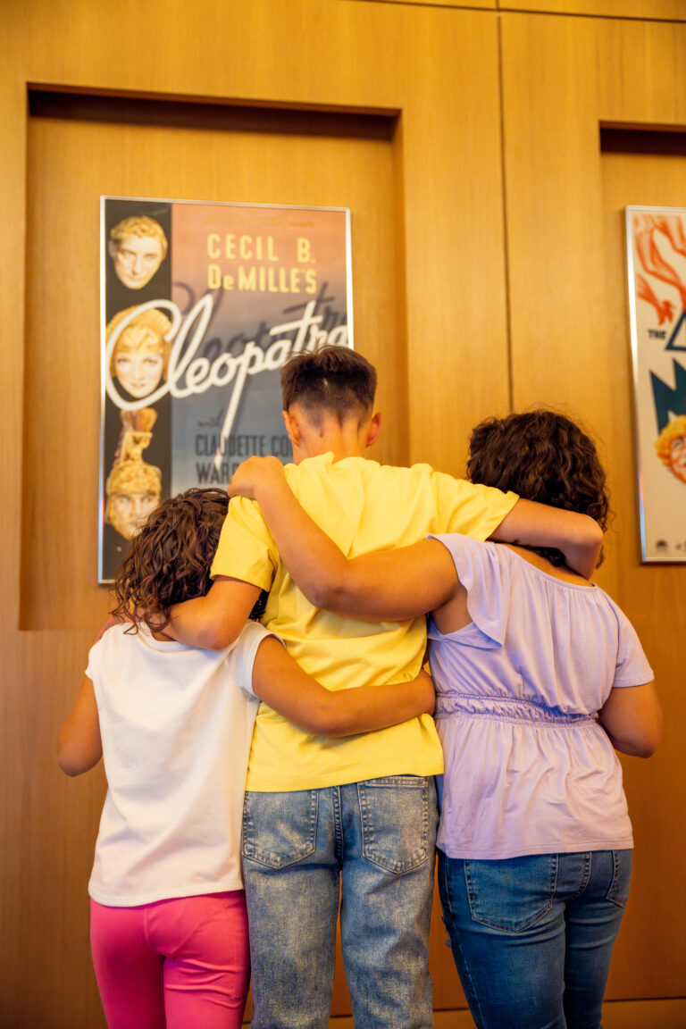 three kids hugging each other in front of a movie poster